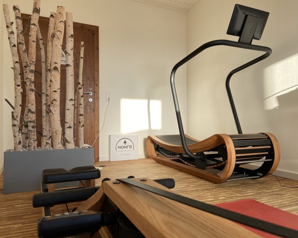 "Modern eingerichtetes Fitnesszimmer mit einem hölzernen Rudergerät, Handgewichten und einer stilvollen Stehlampe"