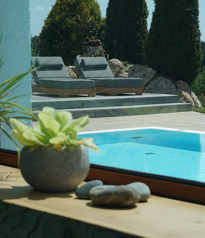Ein eleganter Außenbereich mit einem Swimmingpool, umgeben von Liegestühlen und üppigem Grün, Blick durch ein Fenster mit einer Steinvase im Vordergrund.