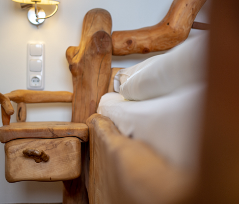Holzstuhl mit rustikaler Optik und weißen Polstern in einem elegant beleuchteten Raum.