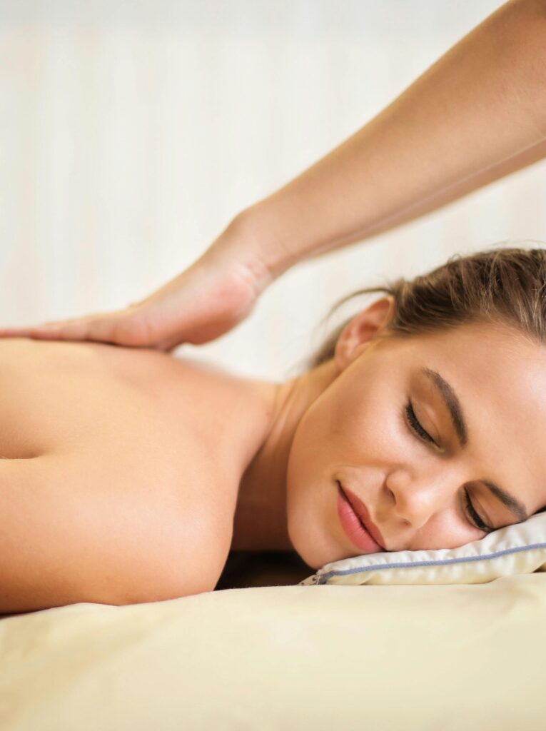 Eine entspannte junge Frau erhält eine Rückenmassage in einem ruhigen Spa-Umfeld.