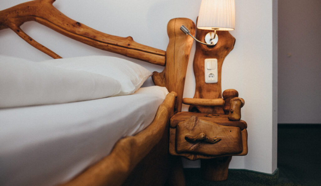 Gemütliches Schlafzimmer mit einem rustikalen Holzbett, weißer Bettwäsche und einer Lampe auf einem Nachttisch.