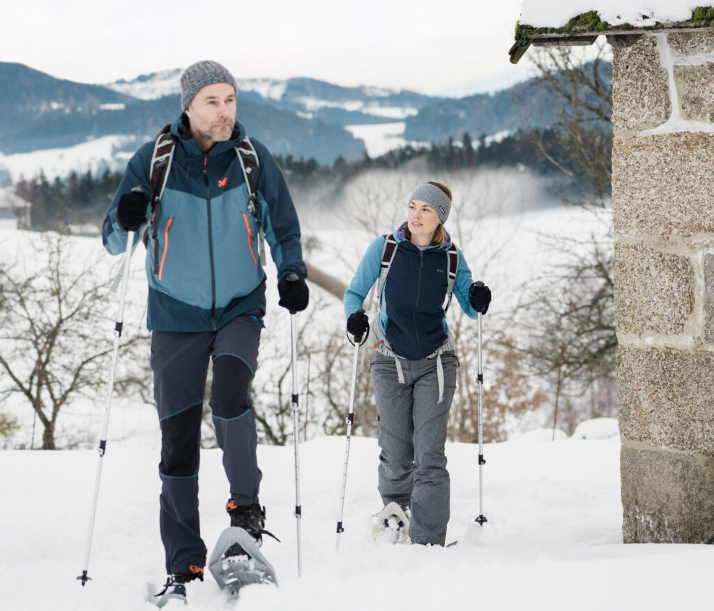 Ein Mann und eine Frau machen Nordic Walking im verschneiten Winterlandschaft.